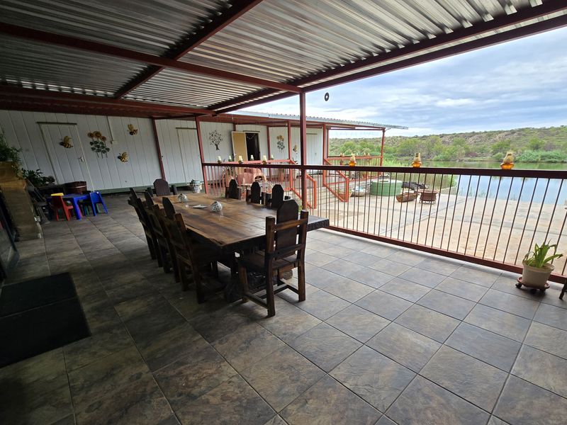 Spacious covered patio featuring tiled flooring, metal roofing, and a protective railing, offering scenic views of the adjacent water and landscape.
