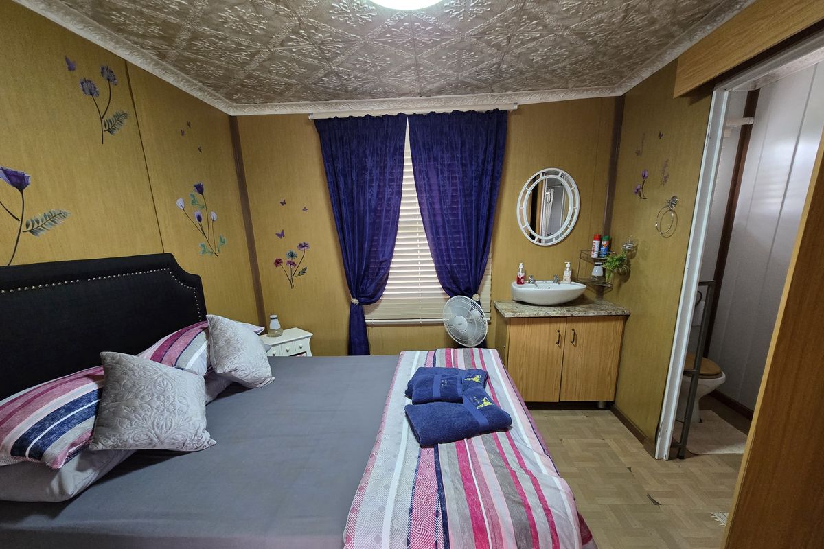 Bedroom featuring an integrated vanity with vessel sink, textured ceiling tiles, and wood-look wall paneling, with an adjoining bathroom area.