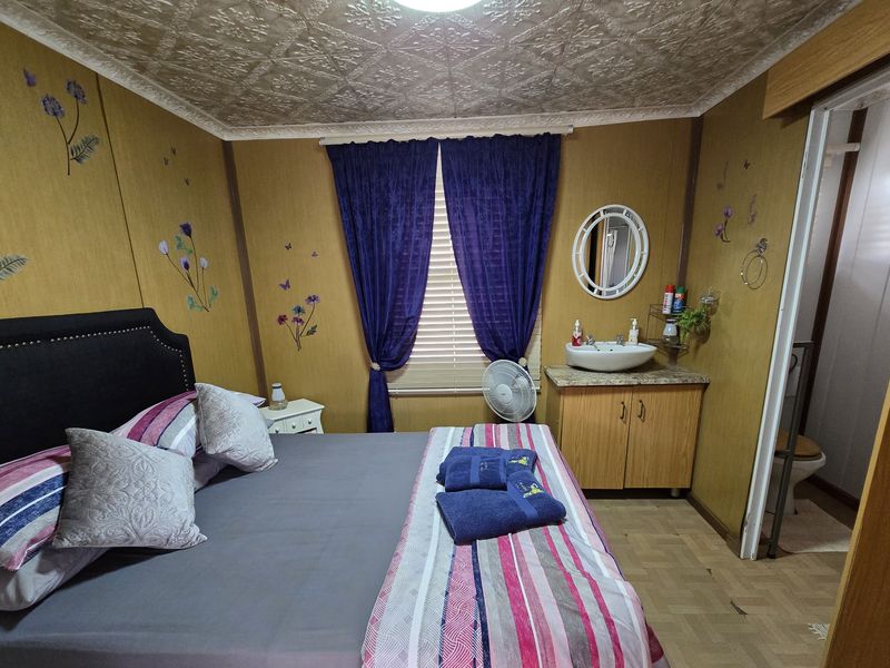 Bedroom featuring an integrated vanity with vessel sink, textured ceiling tiles, and wood-look wall paneling, with an adjoining bathroom area.
