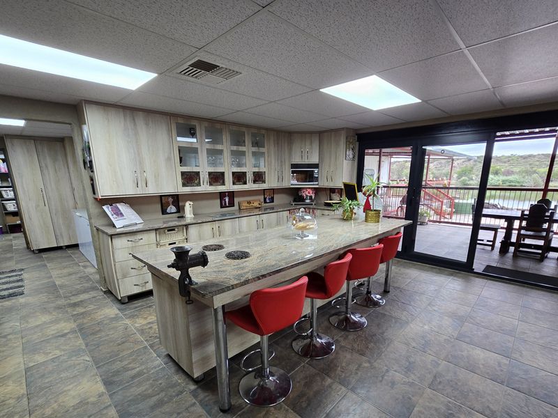 Spacious kitchen featuring light wood cabinetry, a large stone-topped island, tiled flooring, and direct access to an outdoor patio area.