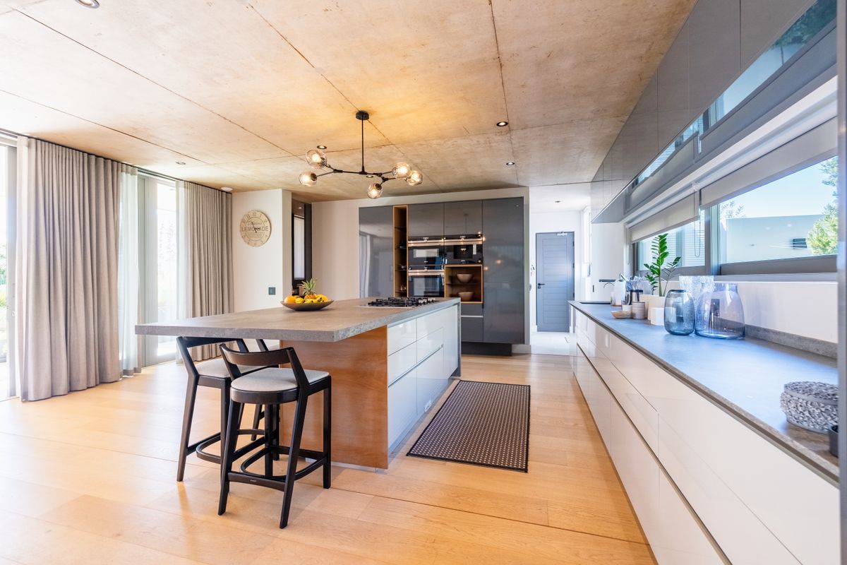 Modern kitchen featuring a large island, integrated appliances, sleek cabinetry, and a unique concrete ceiling, creating a sophisticated and functional culinary space.