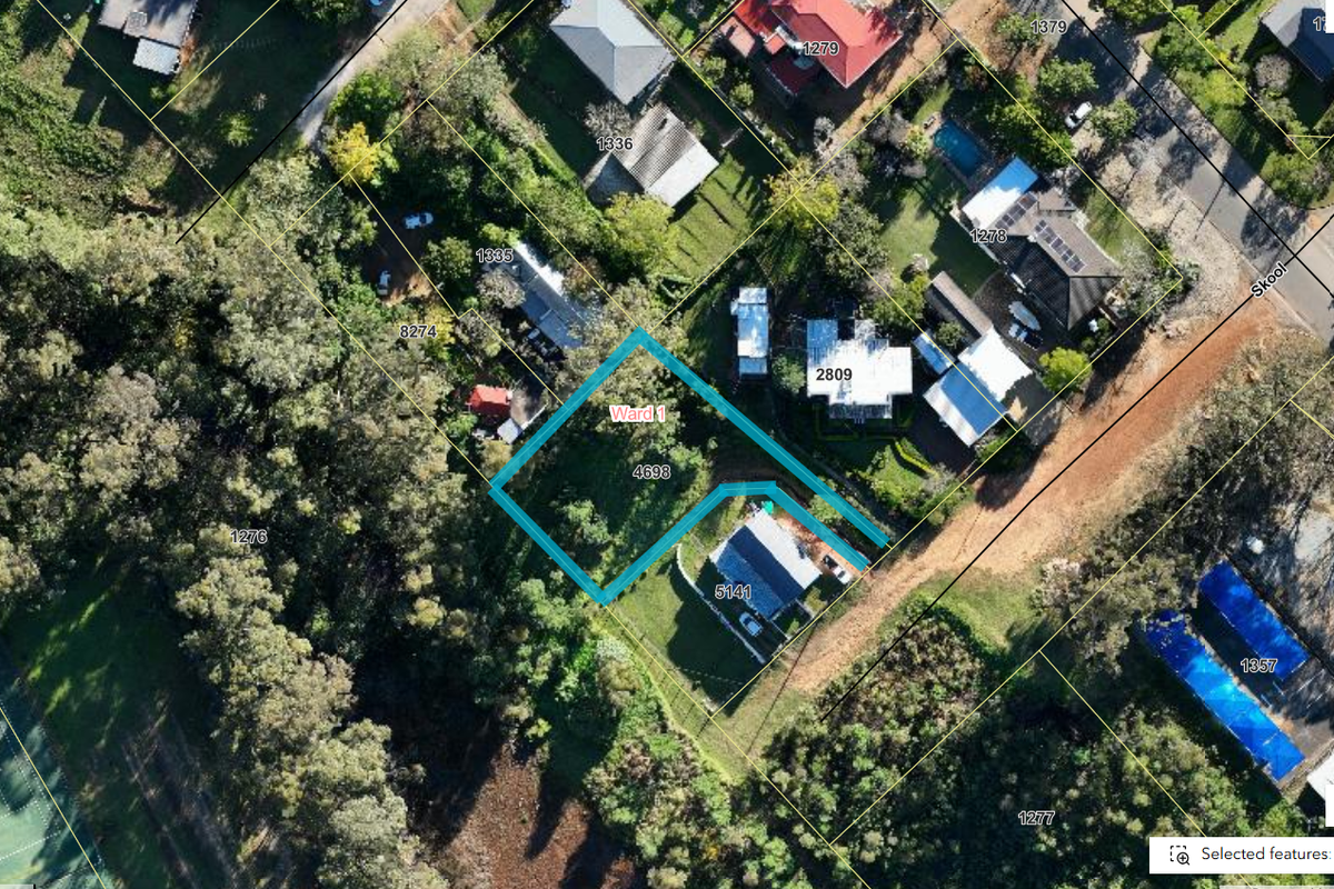 Aerial view of a vacant residential plot featuring established trees and surrounding neighborhood infrastructure.