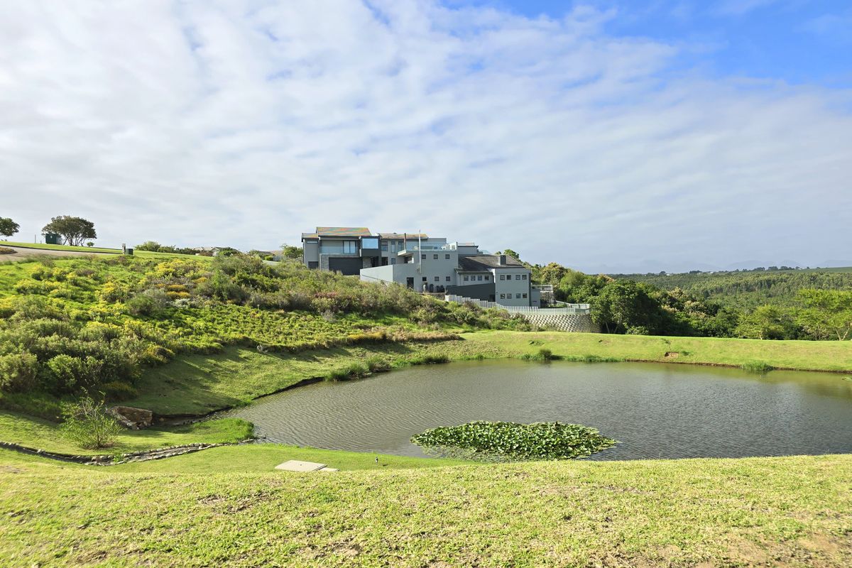 A scenic view of a residential property overlooking a natural pond and landscaped grounds, showcasing the surrounding estate landscape.
