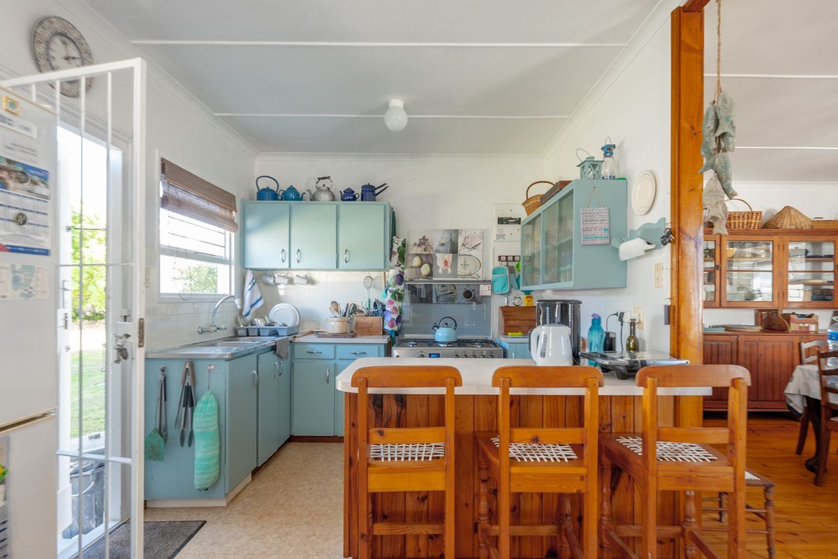 A functional kitchen featuring light blue cabinetry, a breakfast bar, and direct access to the exterior via a security screen door.
