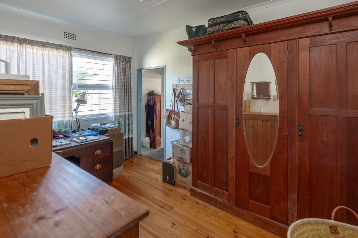 A bedroom featuring timber flooring and a window, providing a functional space with potential for modernization.