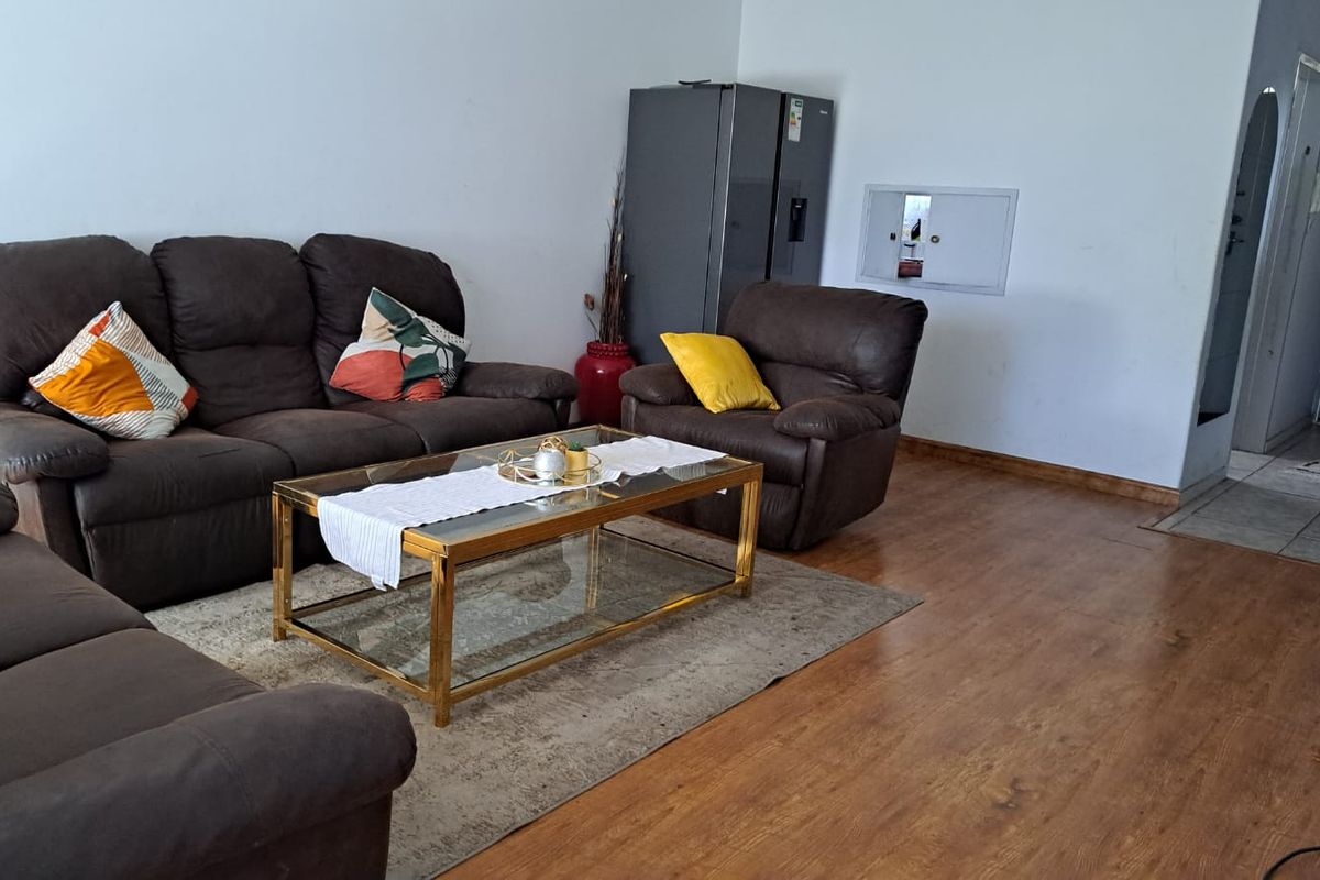 A spacious living area featuring wood-look laminate flooring and neutral wall finishes, providing a comfortable and functional space for relaxation.