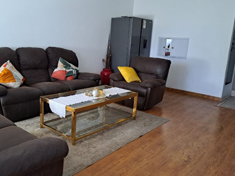 A spacious living area featuring wood-look laminate flooring and neutral wall finishes, providing a comfortable and functional space for relaxation.