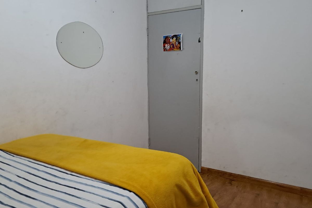 A bedroom featuring laminate flooring and a standard interior door, requiring cosmetic updates to the wall finishes.