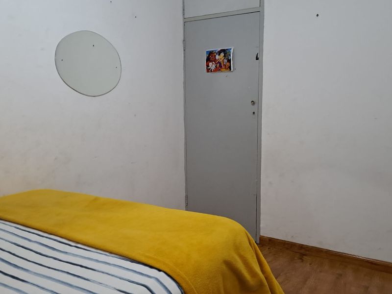 A bedroom featuring laminate flooring and a standard interior door, requiring cosmetic updates to the wall finishes.
