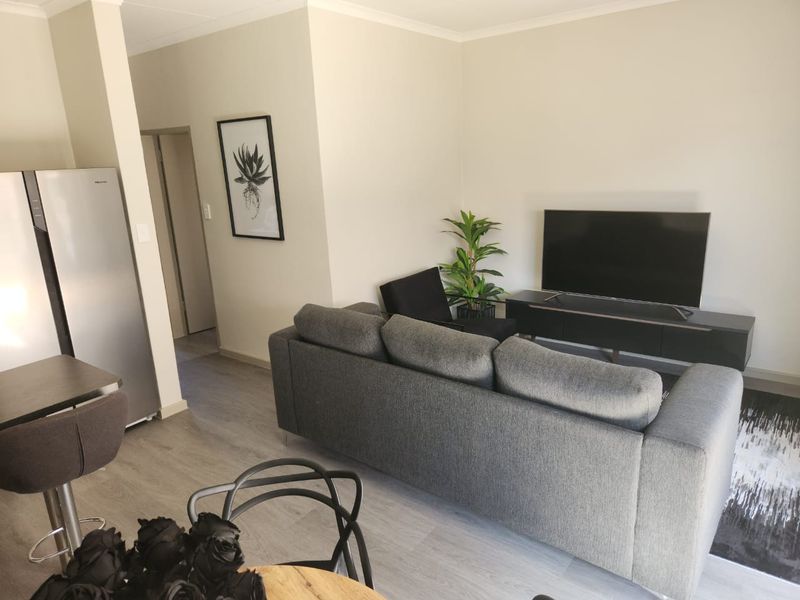 An open-plan living area featuring modern laminate flooring and neutral wall finishes, creating a bright and cohesive space.
