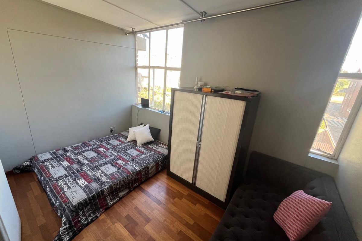 A bedroom featuring laminate flooring and large windows that provide natural light, offering a functional space ready for cosmetic updates.