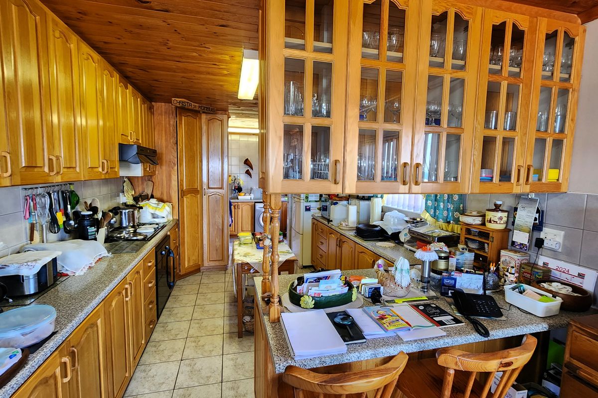 Traditional kitchen featuring extensive wooden cabinetry, glass-fronted display units, laminate countertops, and a timber-clad ceiling, offering a warm and functional workspace.