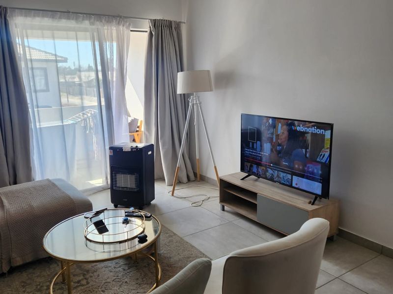 A bright living room featuring large sliding glass doors that provide natural light and access to an outdoor balcony area.
