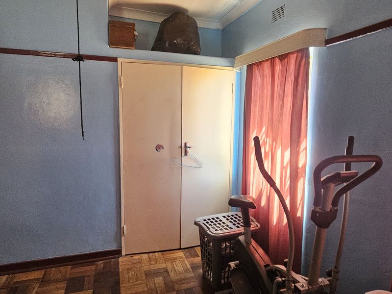 A bedroom featuring original parquet flooring, built-in wardrobe storage, and classic picture rail detailing, offering a blank canvas for renovation.