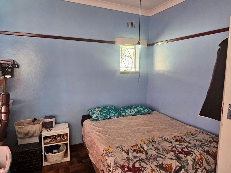 A bedroom featuring classic parquet flooring, a leaded glass window, and traditional picture rail detailing, offering a solid foundation for a modern refresh.