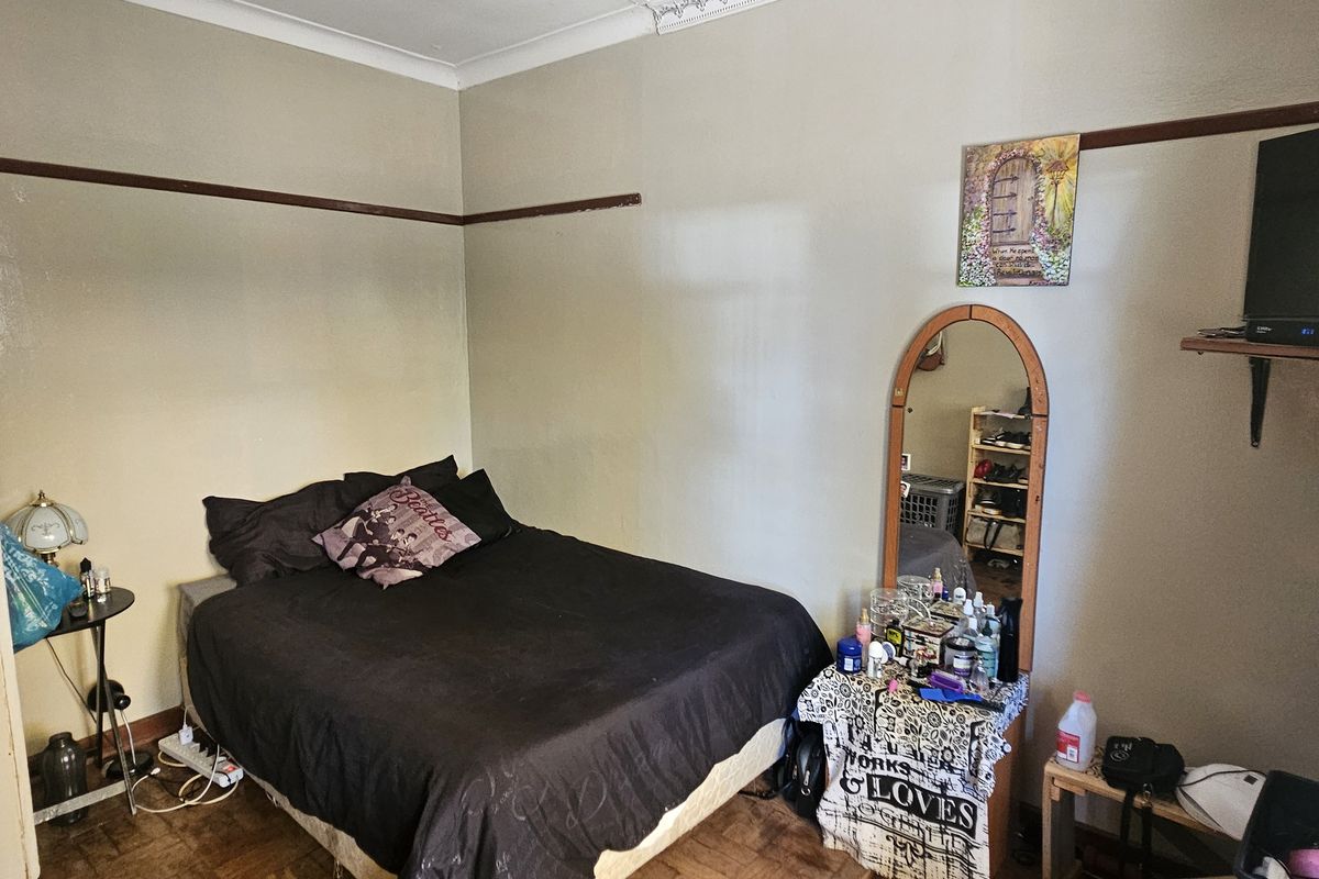 A bedroom featuring parquet flooring, coved ceilings, and a traditional picture rail, offering a functional space with potential for cosmetic updates.
