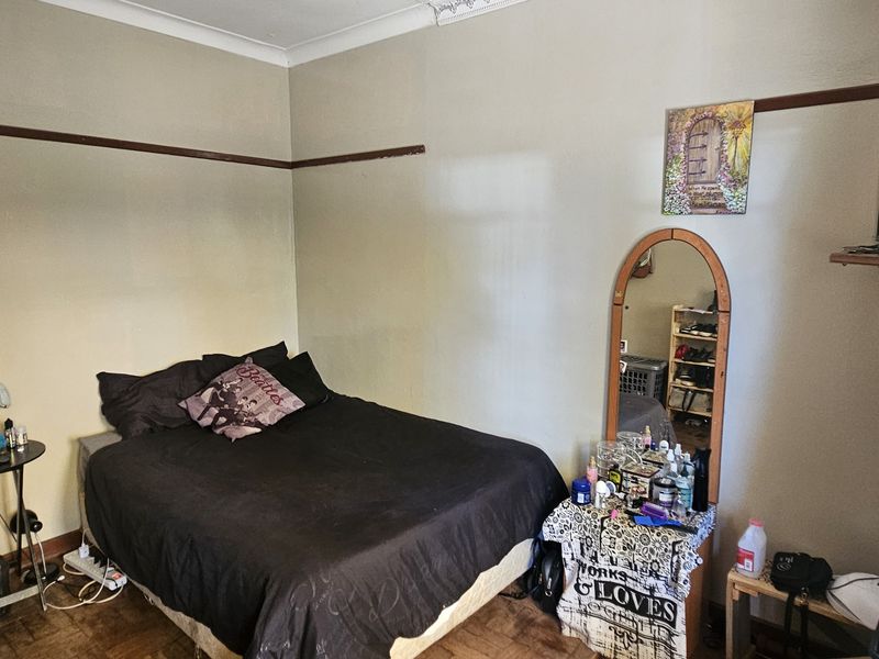 A bedroom featuring parquet flooring, coved ceilings, and a traditional picture rail, offering a functional space with potential for cosmetic updates.