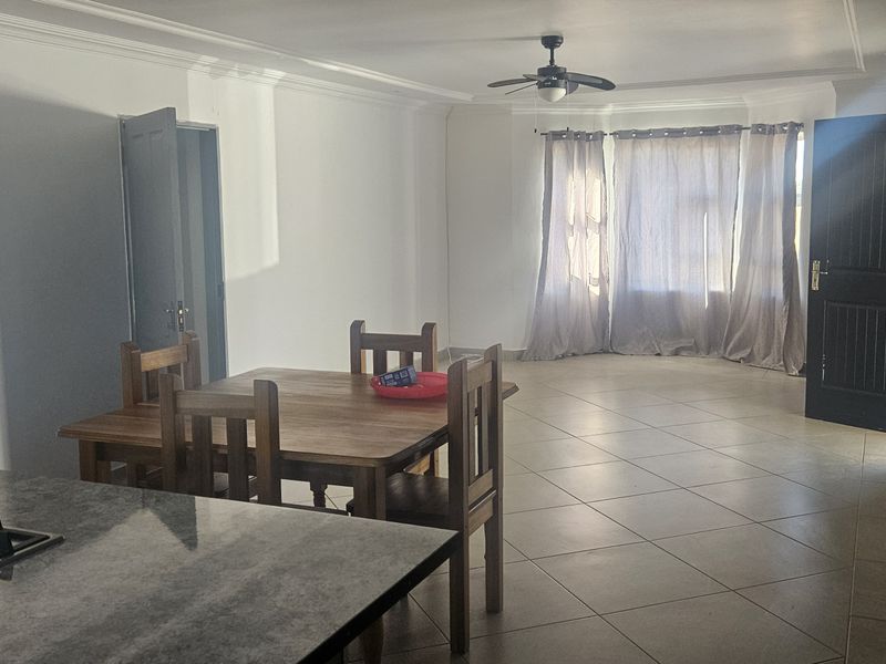 Open plan living and dining area featuring tiled flooring, a ceiling fan, and a kitchen island with a built-in gas hob.