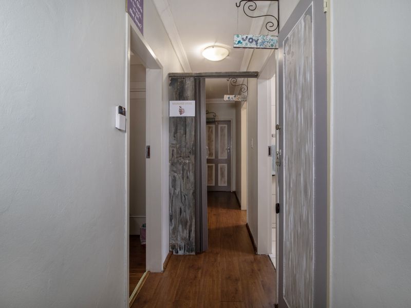 A functional hallway featuring laminate flooring and access to multiple rooms, providing a central circulation space within the home.