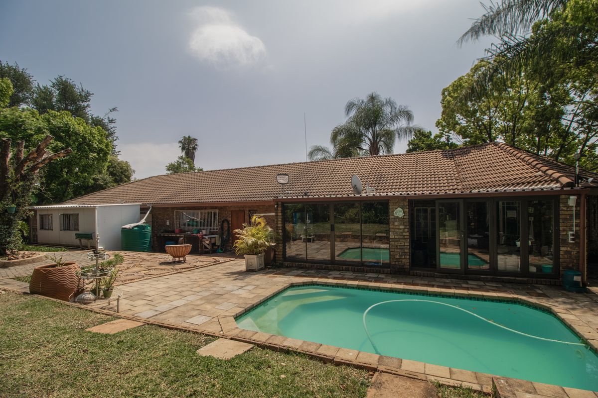 Rear exterior view featuring a swimming pool, paved patio area, and direct access to the home through sliding glass doors.