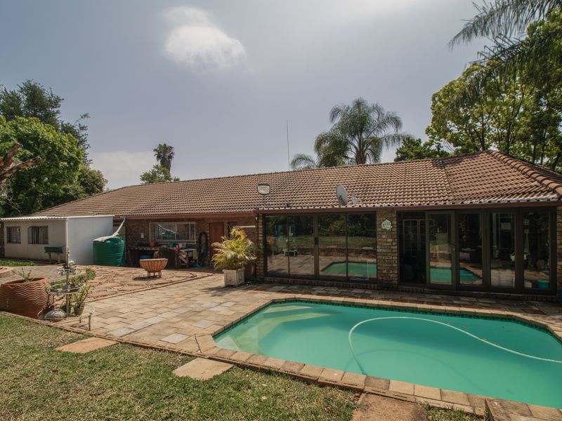 Rear exterior view featuring a swimming pool, paved patio area, and direct access to the home through sliding glass doors.