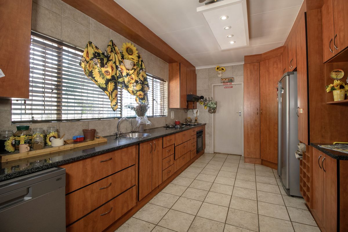 A functional kitchen featuring warm-toned wooden cabinetry, granite countertops, tiled flooring, and integrated appliances, offering ample storage and workspace.