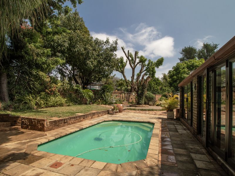 A private outdoor pool area featuring brick paving, a retaining wall, and direct access to the home through large sliding glass doors.