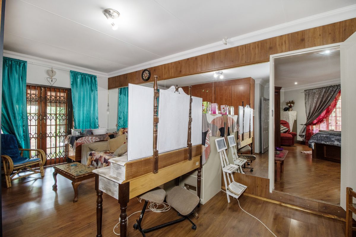 Living room featuring laminate flooring, coved ceilings, and a large built-in mirror wall, with direct access to an exterior security gate.