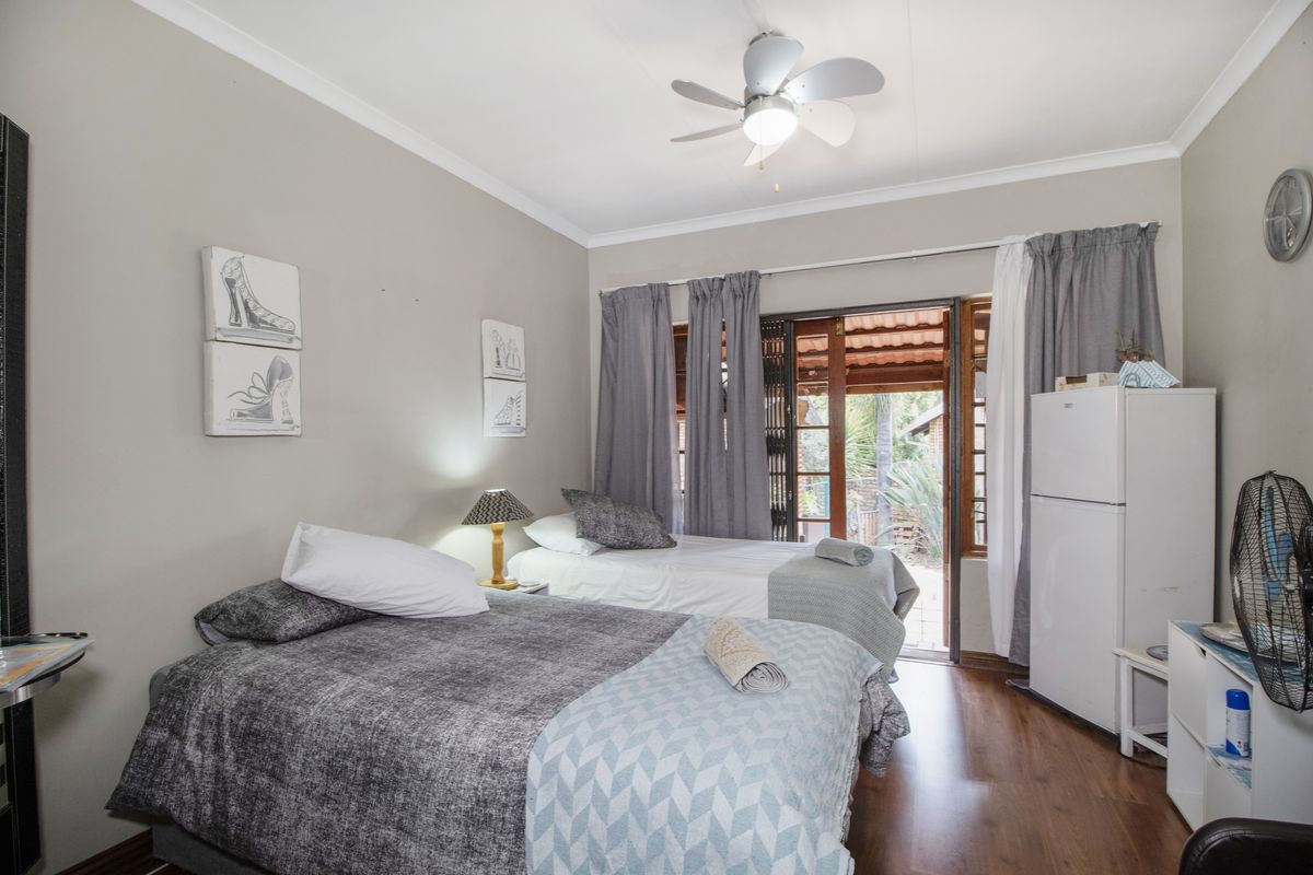 A bedroom featuring laminate flooring, a ceiling fan, and sliding glass doors providing direct access to the outdoor area.