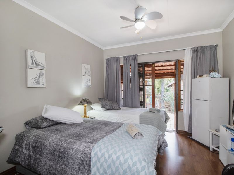 A bedroom featuring laminate flooring, a ceiling fan, and sliding glass doors providing direct access to the outdoor area.