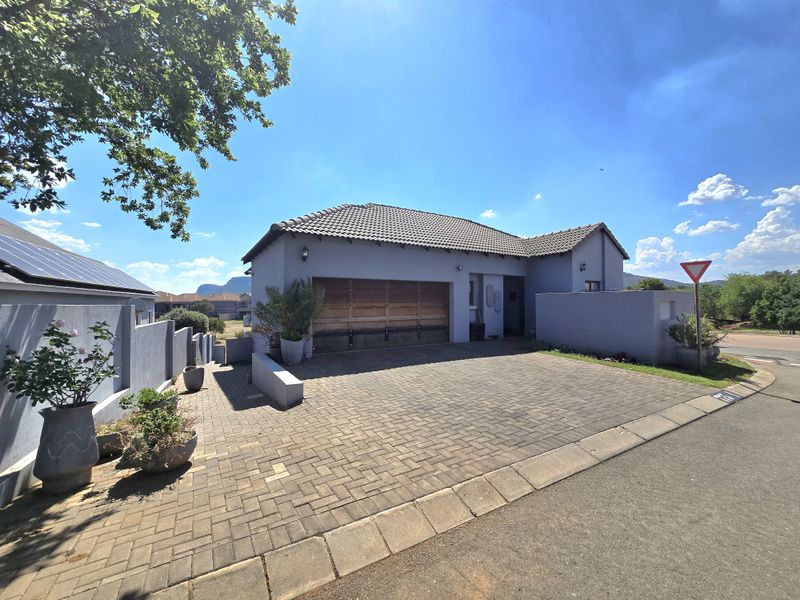 Front exterior view of the property featuring a paved driveway, tiled roof, and a garage with a wooden door.