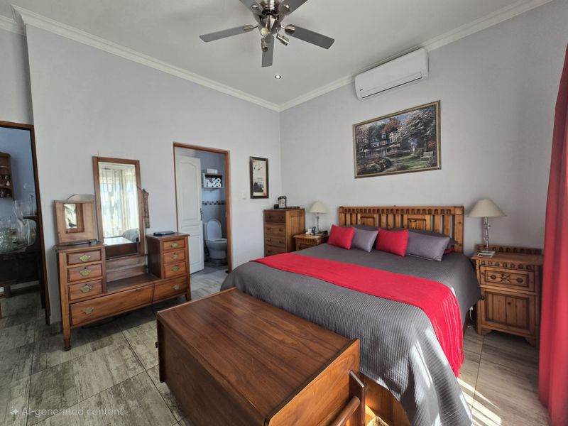 Spacious bedroom featuring tiled flooring, a ceiling fan, and a wall-mounted air conditioning unit, with convenient access to an en-suite bathroom.