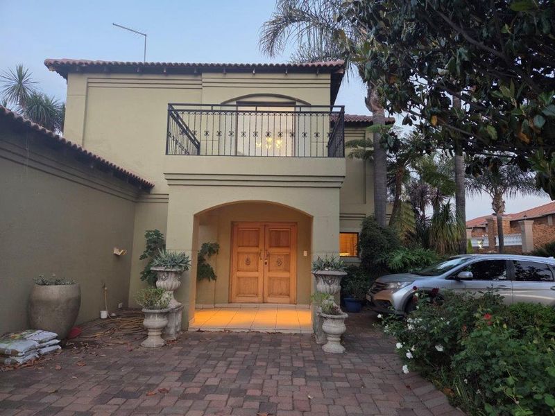 Front elevation of a two-story house featuring a covered entrance with double wooden doors and an upper-level balcony with wrought iron railings.
