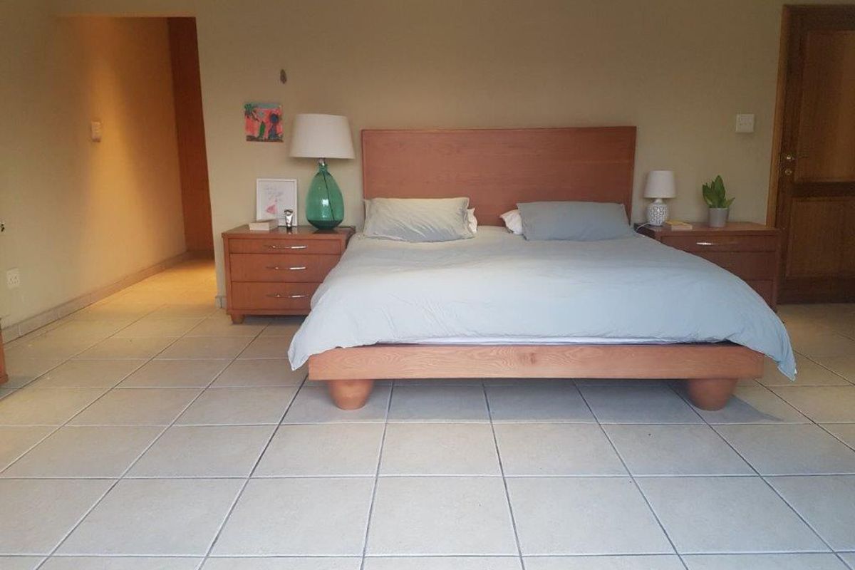 A spacious bedroom featuring neutral wall tones and large format floor tiles, providing a clean and functional living space.