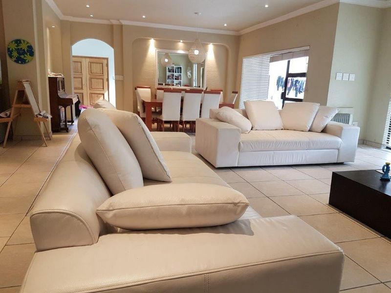 Spacious open-plan living and dining area featuring tiled flooring, recessed lighting, and an arched entryway leading to adjacent rooms.