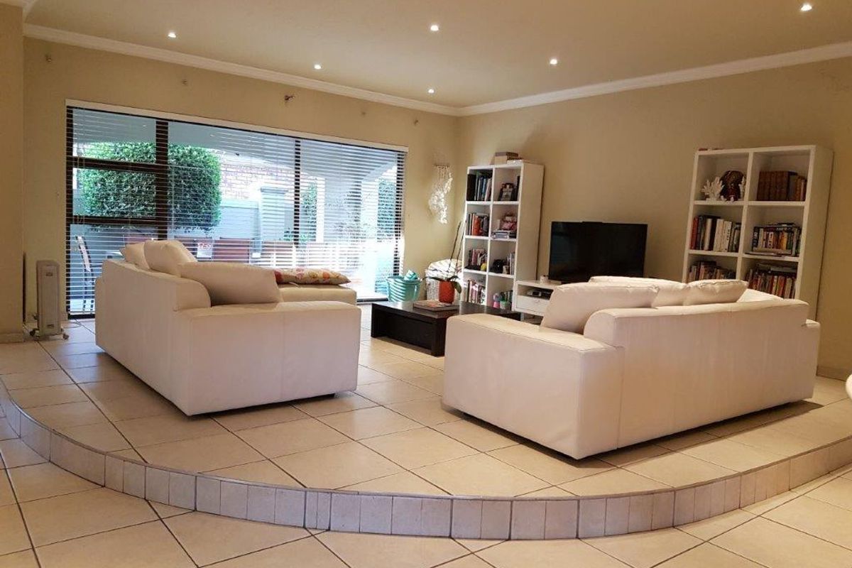 Spacious living room featuring a raised platform area, tiled flooring, recessed downlighting, and large sliding glass doors providing access to the exterior.