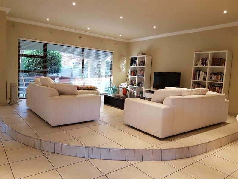 Spacious living room featuring a raised platform area, tiled flooring, recessed downlighting, and large sliding glass doors providing access to the exterior.
