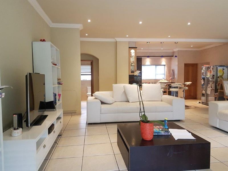 Spacious open-plan living area featuring tiled flooring, recessed lighting, and a seamless flow into the kitchen and dining space.