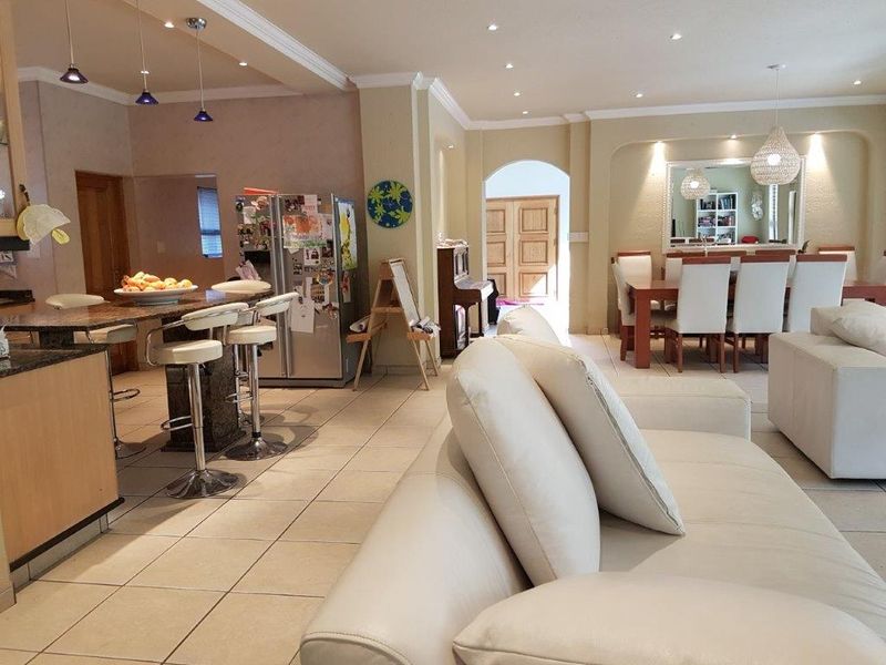 Spacious open-plan living area featuring a kitchen with granite countertops, dining space, and tiled flooring throughout, creating a functional and connected family environment.