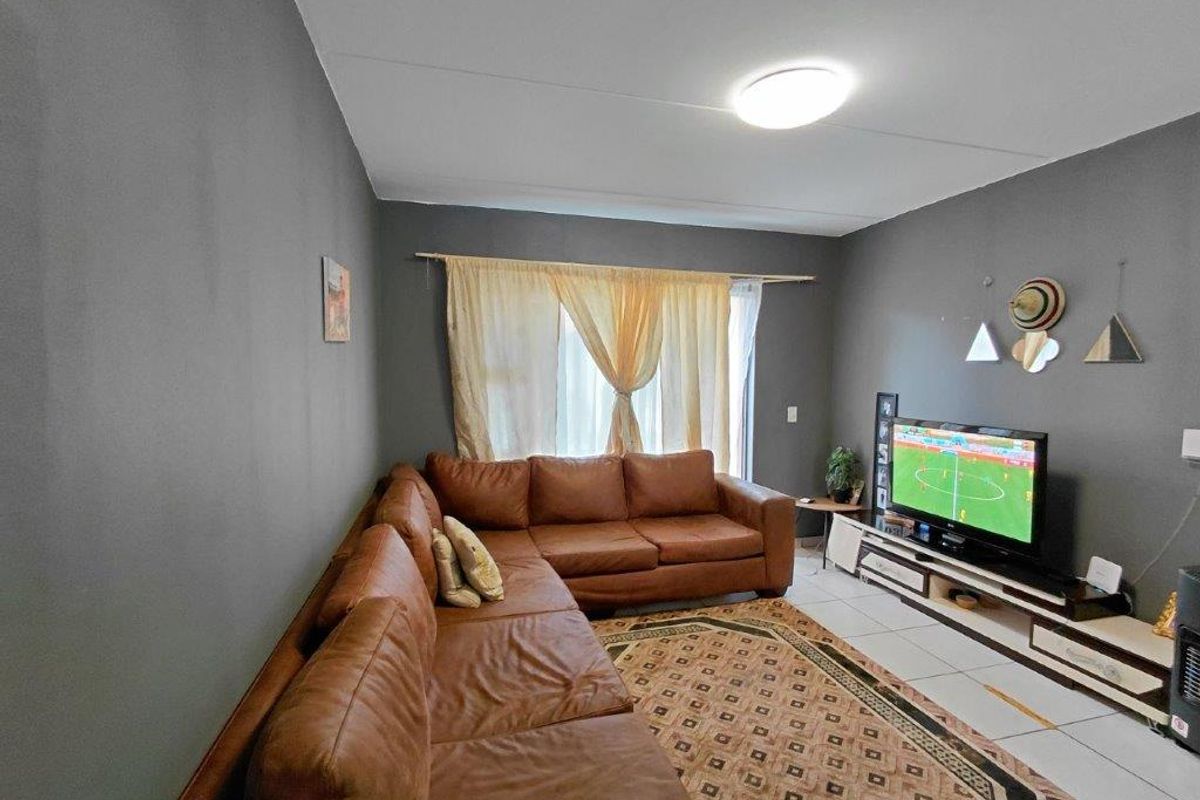 A living room featuring tiled flooring and neutral grey walls, providing a functional and comfortable space for relaxation.