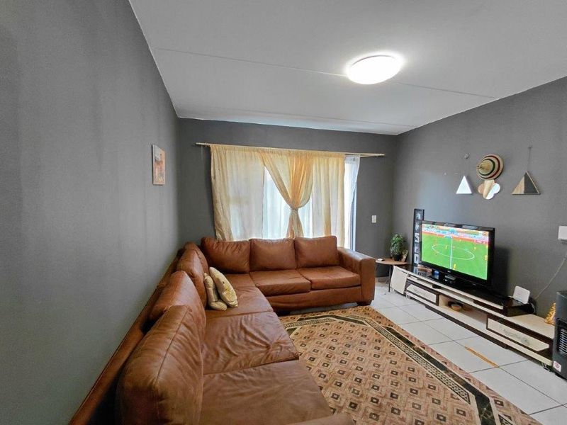 A living room featuring tiled flooring and neutral grey walls, providing a functional and comfortable space for relaxation.
