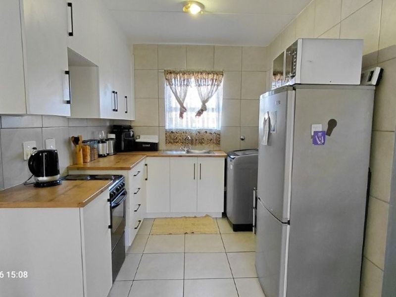 A functional kitchen featuring white cabinetry, wooden countertops, tiled backsplash, and tiled flooring, providing a practical workspace.