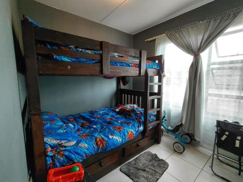 A bedroom featuring tiled flooring and a window with a curtain rod, providing a functional space for rest.