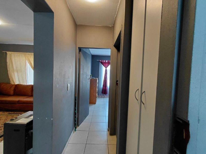 A functional hallway featuring tiled flooring and a built-in cupboard, providing access to adjacent living and bedroom areas.