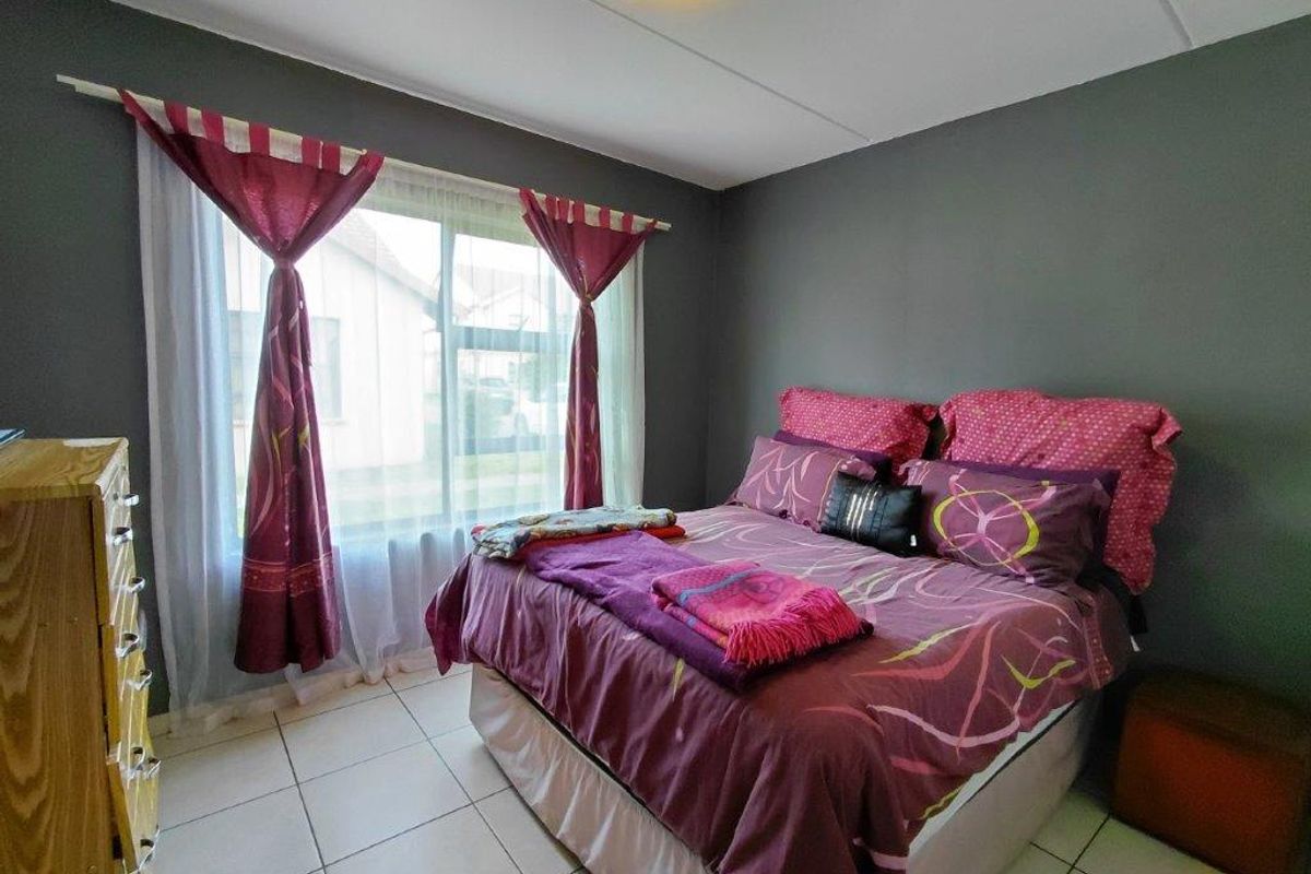 A bedroom featuring tiled flooring and a large window, providing natural light to the space.