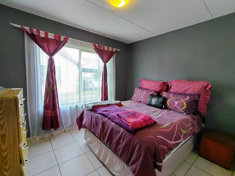 A bedroom featuring tiled flooring and a large window, providing natural light to the space.