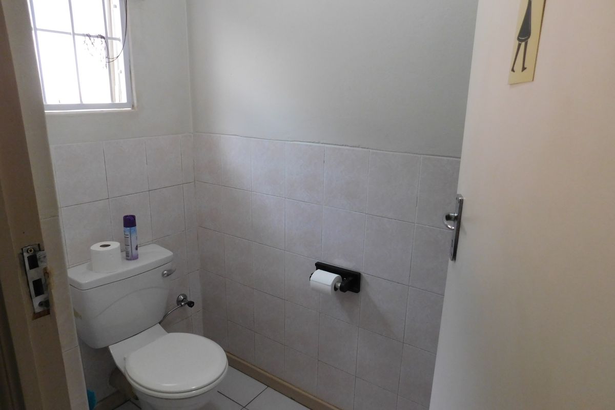 A functional guest bathroom featuring tiled walls, tiled flooring, and a standard toilet suite.