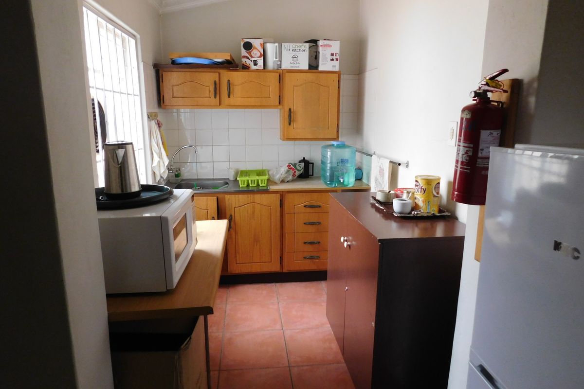 A functional kitchen featuring wooden cabinetry, tiled backsplash, and ceramic floor tiles, providing a practical workspace with essential built-in storage and fixtures.