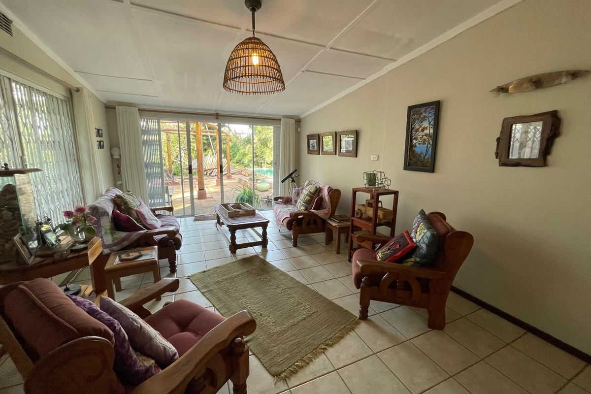 A comfortable living room featuring tiled flooring and large sliding glass doors that provide direct access to the outdoor patio and garden area.