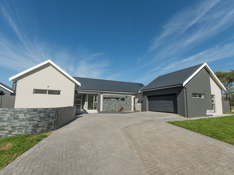 Modern single-story house featuring a paved driveway, stone-clad accents, and a double garage with a contemporary gabled roof design.